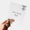 Hand houdt wenskaart hennafeest vast met illustratie van Marokkaanse bruid en tekst 'It's your Henna day'.